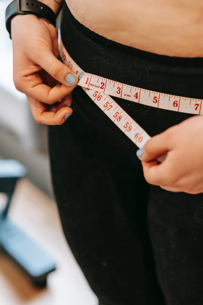 A woman measures her waist for exercise purposes.