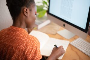 A woman engaging in healthy aging while writing in front of a computer.